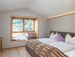 Schlafzimmer mit Doppelbett und Sitzfenster - Alpegg Chalets in Waidring, Tirol.