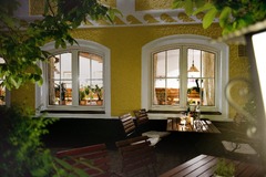 Die Hoftaverne Ziegelböck präsentiert sich hier mit einem besonders gemütlichen Außenbereich: Der stimmungsvoll beleuchtete Gastgarten mit gedeckten Tischen, warmer Fassadengestaltung und Blick ins einladende Innere unterstreicht den charmanten Charakter 