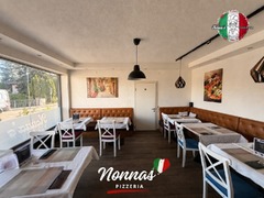 Der gemütlich eingerichtete Gastraum von Nonna’s Pizzeria in Seiersberg bietet gedeckte Tische, bequeme Sitzbänke und eine entspannte Atmosphäre.